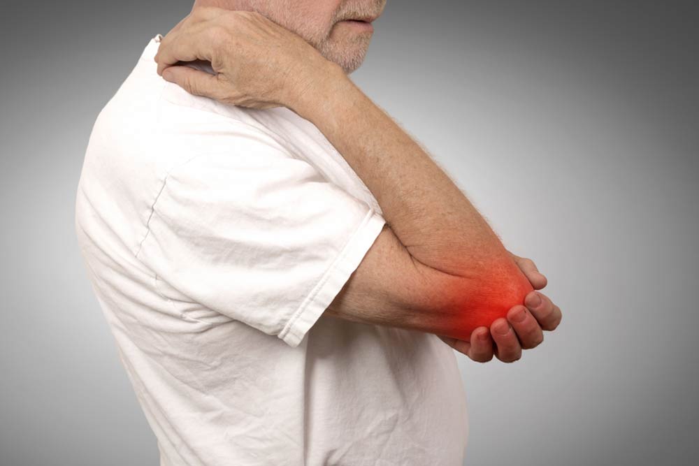 Closeup senior man with elbow inflammation colored in red suffering from pain and rheumatism isolated on gray wall background