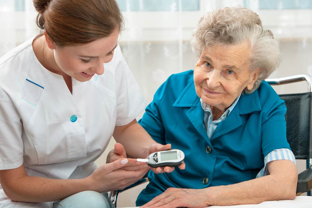 Female nurse measuring blood glucose level of senior woman